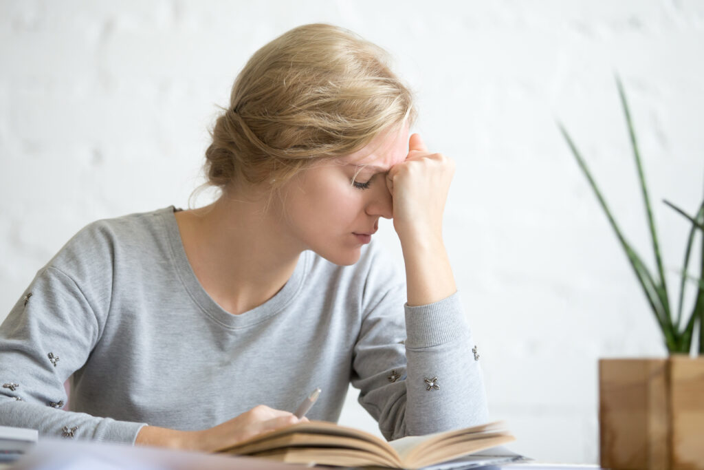 young woman overworked student girl sitting at the table